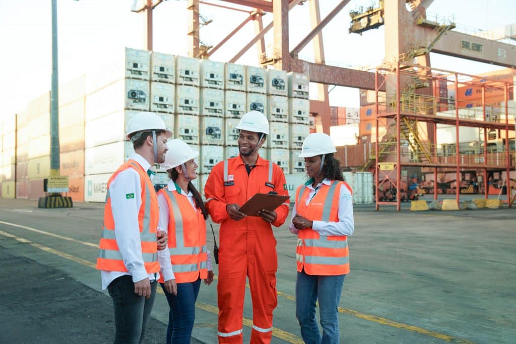 Equipe Norcoast planeja transporte de carga refrigerada em porto, com contêineres reefer ao fundo.